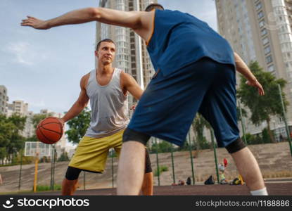 Two players in the center of the basketball field on outdoor court. Male athletes in sportswear play the game on streetball training. Two players in the center of basketball field