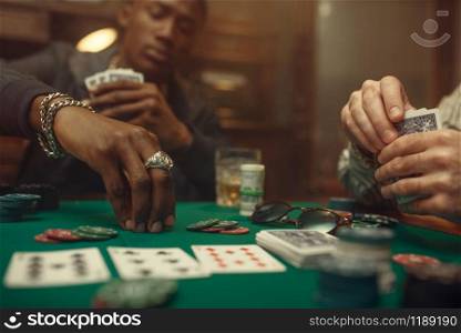 Two poker players place bets on gaming table with green cloth in casino. Games of chance addiction, risk, gambling house. Men leisures with whiskey and cigars