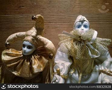 Two porcelain harlequin puppet on a wooden background