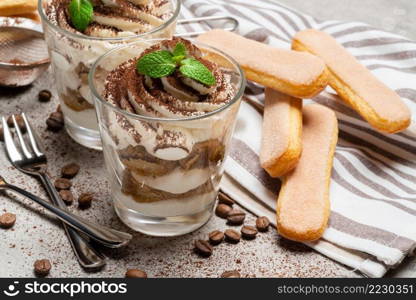 two portions Classic tiramisu dessert in a glass on concrete background or table. two portions Classic tiramisu dessert in a glass on concrete background