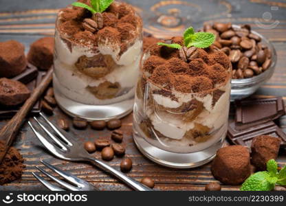 two portions Classic tiramisu dessert in a glass on wooden background or table. two portions Classic tiramisu dessert in a glass on wooden background