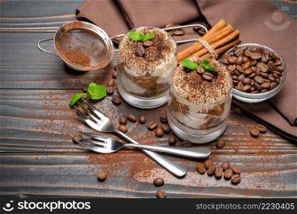 two portions Classic tiramisu dessert in a glass on wooden background or table. two portions Classic tiramisu dessert in a glass on wooden background