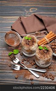 two portions Classic tiramisu dessert in a glass on wooden background or table. two portions Classic tiramisu dessert in a glass on wooden background