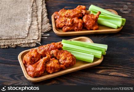 Two portions of buffalo wings with fresh celery stalks