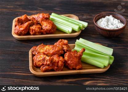 Two portions of buffalo wings with fresh celery stalks and blue cheese dip