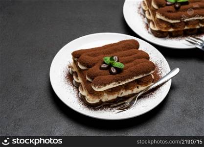 Two portions of Classic tiramisu dessert on ceramic plate on concrete background or table. Two portions of Classic tiramisu dessert on ceramic plate on concrete background