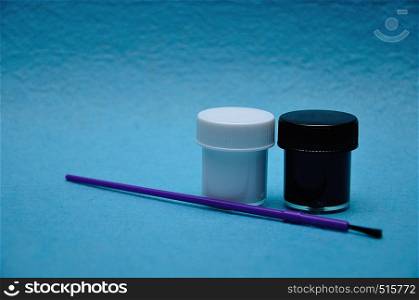 Two pots of paint with a purple paintbrush on a blue background