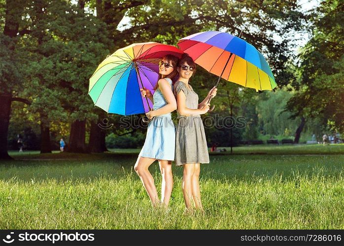 Two pretty ladies holding colorful, huge umbrellas