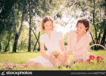 Two pretty ladies in park with their cute pet. In park with loving pet