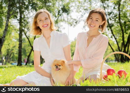 Two pretty ladies in park with their cute pet. In park with loving pet