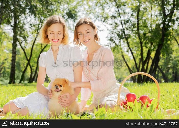 Two pretty ladies in park with their cute pet. In park with loving pet