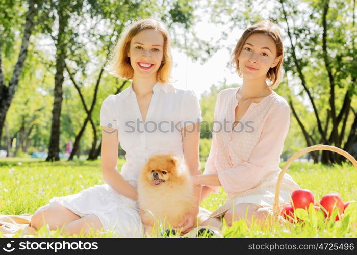 Two pretty ladies in park with their cute pet. In park with loving pet