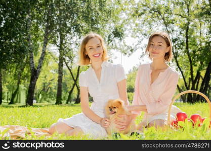 Two pretty ladies in park with their cute pet. In park with loving pet