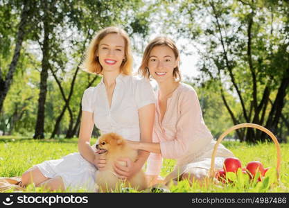 Two pretty ladies in park with their cute pet. In park with loving pet