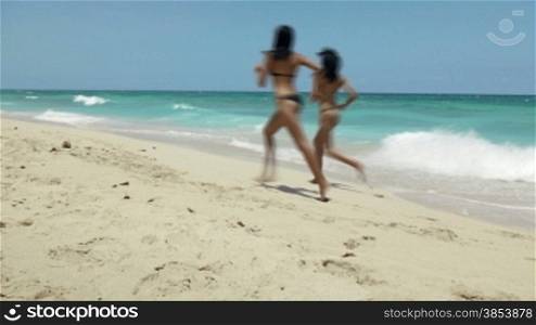 Two pretty latina sisters in bikini having fun on beach near Caribbean sea