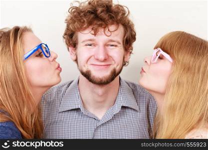 Two pretty women kissing handsome man. Love triangle.. Two pretty women kissing handsome man.