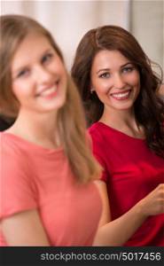 Two pretty Women shopping clothes. Shopper looking at camera indoors in store. Beautiful happy smiling caucasian females models.