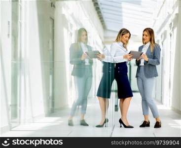 Two pretty young business women with digital tablet in the office hallway