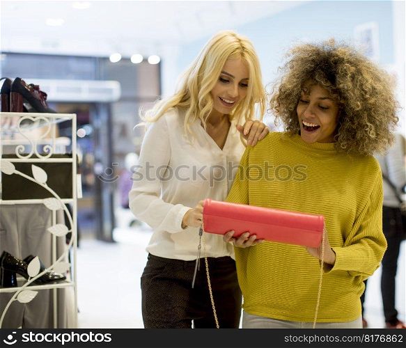 Two pretty young multiethnic women buying purse in the store