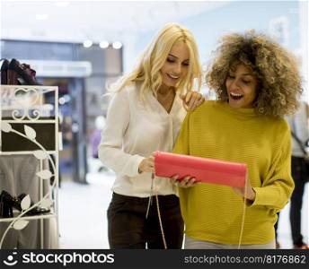 Two pretty young multiethnic women buying purse in the store