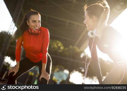 Two pretty young women doing gymnastic exercises outdoor in urban enviroment