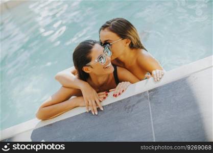 Two pretty young women relaxing in the pool at sunny day
