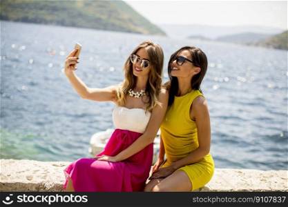 Two pretty young women taking selfie on vacation by the sea
