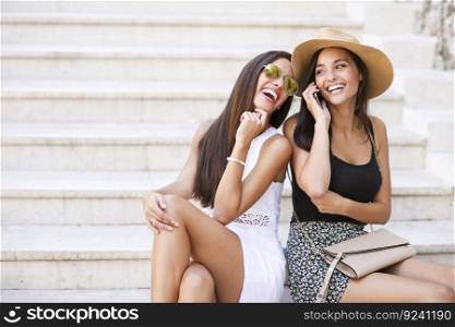 Two pretty young women talking on the mobi≤pho≠at∑mer day