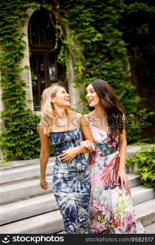 Two pretty young women walking by the old house with ivy