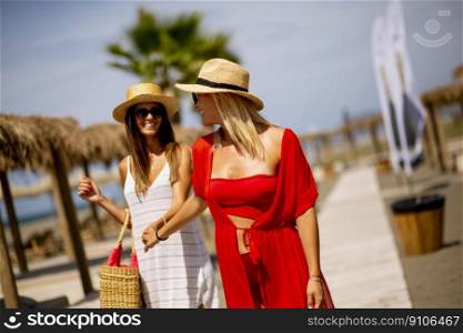 Two pretty young women walking on a beach at summer