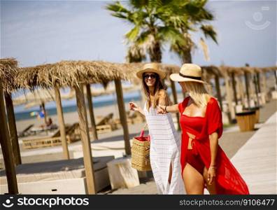 Two pretty young women walking on a beach at summer