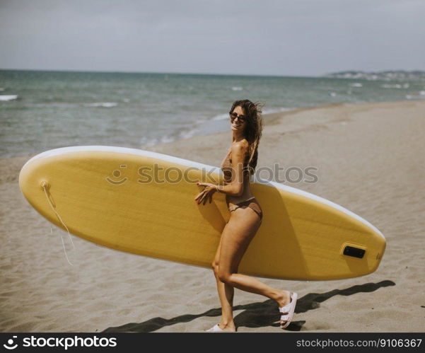 Two pretty young women with paddle board on the beach on a summer day