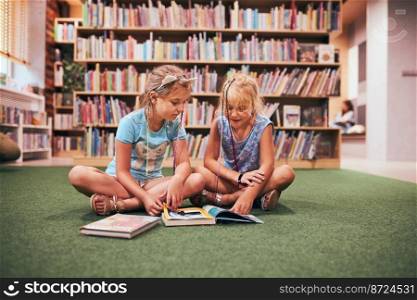 Two primary students reading books in school library. Schoolgirls learning from books. Pupils doing homework. Children having fun in school club. Back to school