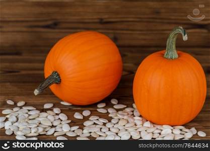Two Pumpkins and many seeds on wooden background. Pumpkins and seeds