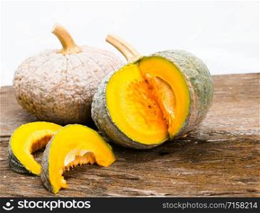two pumpkins on wood with two slices of pumpkin