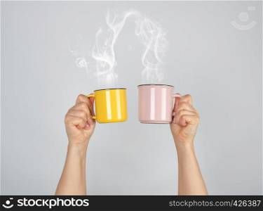 two raised hands up with ceramic cups, thick steam comes out of the mug and connects, love concept