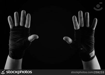 two raised up palms of a man wrapped in a black textile bandage, black and white toning