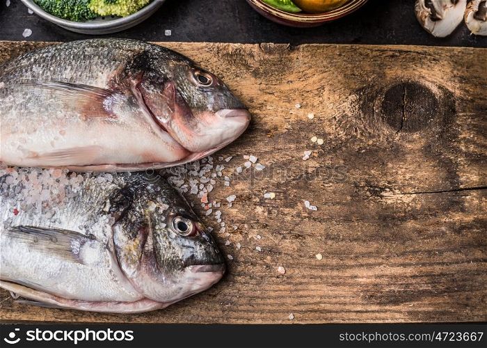 Two raw dorado fishes on rustic wooden background, top view