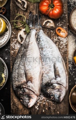 Two raw dorado fishes on wooden background with cooking ingredients, top view. Seafood concept