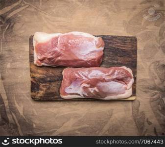 Two raw duck breast on a cutting board on wooden rustic background top view close u
