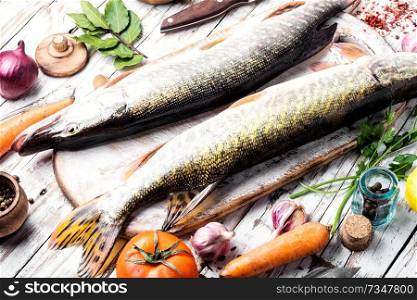 Two raw pike with spices on an old wooden background.Raw fish with spices for cooking.. Fish pike on the kitchen board