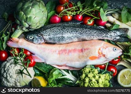Two raw Trout fishes with fresh vegetables ingredients for healthy clean cooking, top view