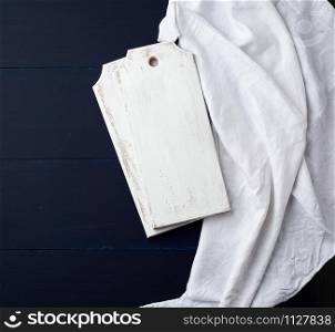 two rectangular white cutting kitchen boards on a blue wooden background, next to a white textile towel, top view. Copy space