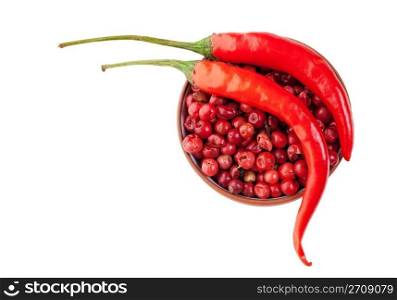 Two red chili peppers resting on a bowl of red peppercorns. Ingredients ready to be added to a hot dish. Shot on white background.