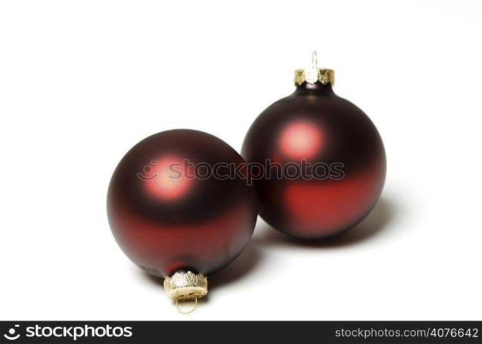 Two red christmas tree ornaments over white