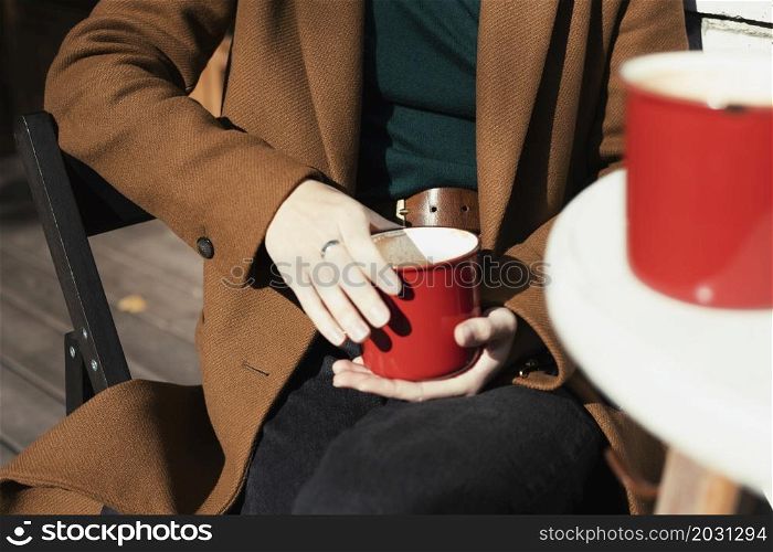 two red cups of coffee on the table. girl with a red cup of cappuccino in her hands