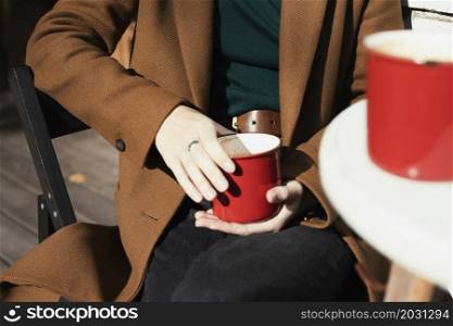 two red cups of coffee on the table. girl with a red cup of cappuccino in her hands