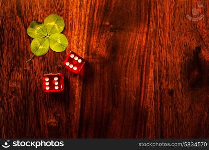 Two red dices with a luckycharm four-leaf clover