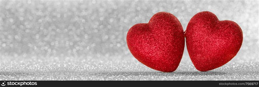Two red glitter hearts on bright silver lights bokeh background Valentines day card. Two hearts on bokeh background