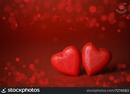 Two red handmade wooden hearts on red lights bokeh background. Red hearts on glitter background